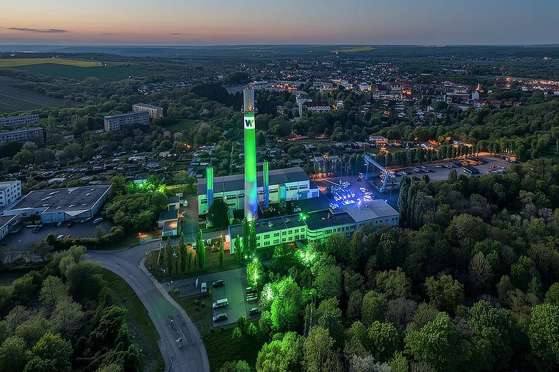 Stadtwerk Weißenfels bei Nacht mit markantem Schornstein ist grün und blau angeleuchtet