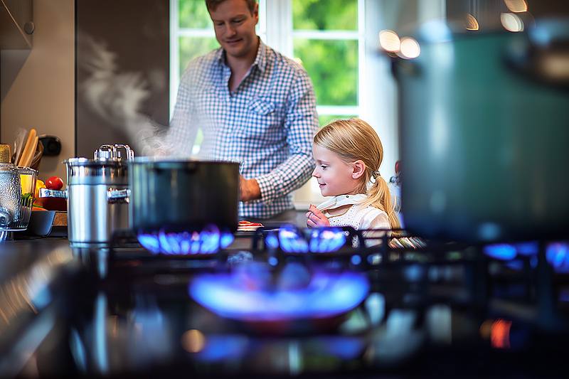 Vater kocht mit seiner Tochter in einer Küche auf dem Gasherd